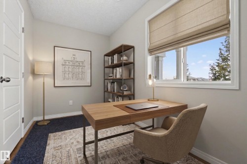 This room features a window with a roller shade, light-colored walls, and a desk - 15 2072 Wonnacott Way, Edmonton, AB - Indoor Photo Showing Office