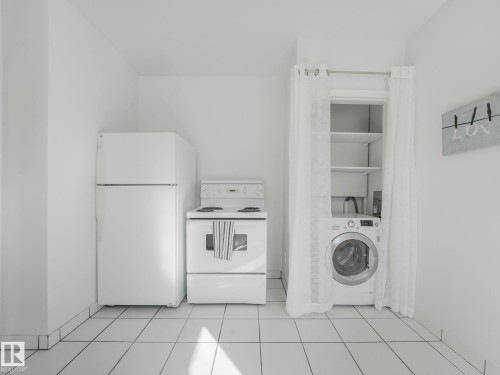 The property features white appliances, including a refrigerator, stove, and a front-loading washer - 10645 62 Avenue, Edmonton, AB - Indoor Photo Showing Laundry Room