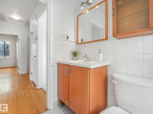 Bathroom with a wood vanity featuring a white countertop and a mirror with track lighting - 10645 62 Avenue, Edmonton, AB - Indoor Photo Showing Bathroom