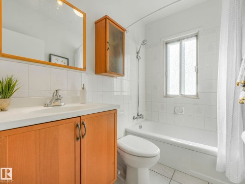 Bathroom featuring white tiled walls, a window, and a bathtub with a shower - 10645 62 Avenue, Edmonton, AB - Indoor Photo Showing Bathroom