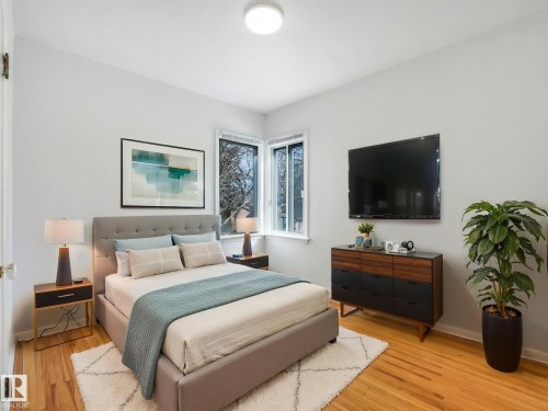 This bedroom features hardwood flooring and light-colored walls, providing a bright and airy atmosphere - 10645 62 Avenue, Edmonton, AB - Indoor Photo Showing Bedroom