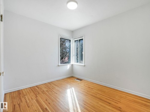 This room features hardwood floors and two windows that provide natural light - 10645 62 Avenue, Edmonton, AB - Indoor Photo Showing Other Room