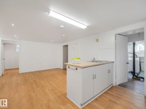 Open concept living area with light wood flooring, recessed lighting, and a kitchen island featuring a sink and white cabinetry - 10645 62 Avenue, Edmonton, AB - Indoor Photo Showing Other Room