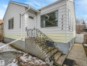 The property features white and yellow siding, a white front door with an arched window, and a black wrought iron handrail leading to the entrance - 10645 62 Avenue, Edmonton, AB  - Outdoor 