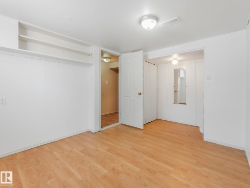 This room features light-toned wood flooring, a white ceiling with a flush-mount light fixture, and white walls - 10645 62 Avenue, Edmonton, AB - Indoor Photo Showing Other Room