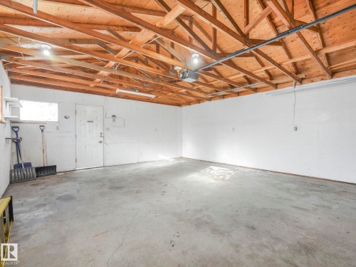 Spacious utility room featuring a concrete floor, exposed wood ceiling beams, and white painted walls - 10645 62 Avenue, Edmonton, AB - Indoor Photo Showing Garage