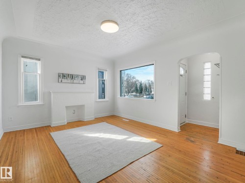 The property features hardwood floors, a white fireplace, and multiple windows providing natural light - 10645 62 Avenue, Edmonton, AB - Indoor