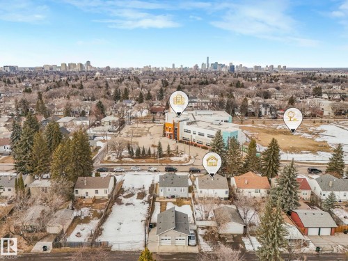 This aerial view highlights the property's advantageous position within a residential neighborhood, offering views of a distant city skyline - 10645 62 Avenue, Edmonton, AB - Outdoor With View