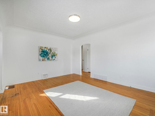 Bright living space featuring hardwood floors, white walls, and a ceiling light fixture - 10645 62 Avenue, Edmonton, AB - Indoor Photo Showing Other Room