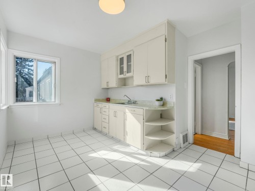 The kitchen features white cabinetry, a light-colored countertop, and a window providing natural light - 10645 62 Avenue, Edmonton, AB - Indoor