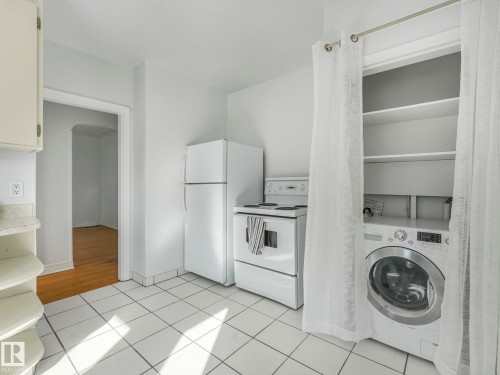 The kitchen features a white electric range, a white refrigerator, and white tiled flooring - 10645 62 Avenue, Edmonton, AB - Indoor Photo Showing Laundry Room