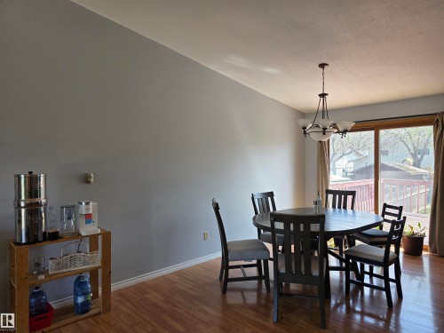 Dining area with wood-finish flooring, a contemporary chandelier, and a sliding glass door providing access to an exterior deck - 4029 55 Avenue, Drayton Valley, AB - Indoor Photo Showing Dining Room