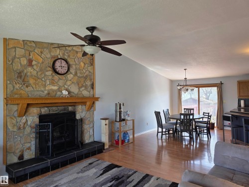 Stone-faced fireplace with a wood mantel and black tile hearth - 4029 55 Avenue, Drayton Valley, AB - Indoor Photo Showing Other Room With Fireplace