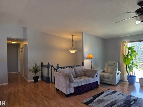 Open living area featuring wood-finish flooring, a ceiling fan, and a large sliding glass door - 4029 55 Avenue, Drayton Valley, AB - Indoor Photo Showing Living Room