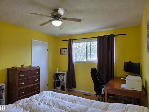 Bright interior room featuring a ceiling fan with integrated lighting, wood-finish flooring, and a window with a dark curtain rod - 4029 55 Avenue, Drayton Valley, AB - Indoor Photo Showing Bedroom