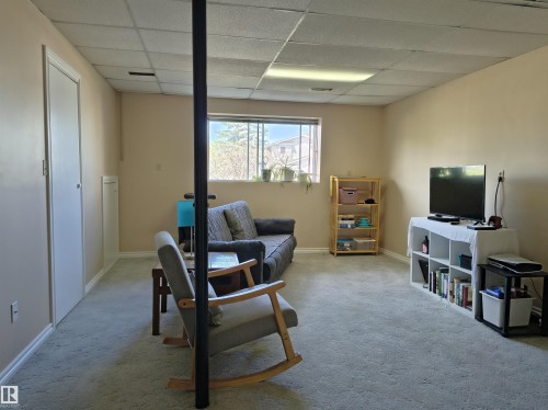 Carpeted living space featuring a drop ceiling with recessed lighting, a window providing natural light, and neutral-toned walls - 4029 55 Avenue, Drayton Valley, AB - Indoor