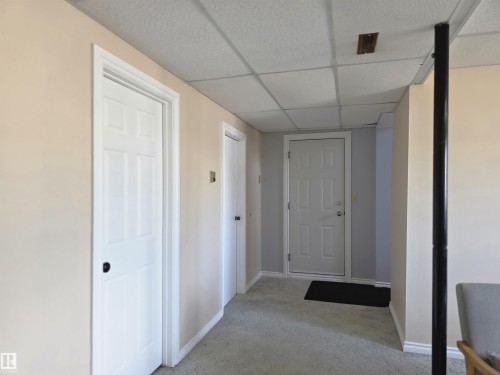 Interior space featuring light beige walls, white six-panel doors with black hardware, and a dropped ceiling with acoustic tiles - 4029 55 Avenue, Drayton Valley, AB - Indoor Photo Showing Other Room