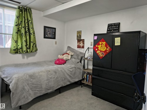 Carpeted room with a window featuring blinds and a vibrant green patterned curtain - 4029 55 Avenue, Drayton Valley, AB - Indoor Photo Showing Bedroom