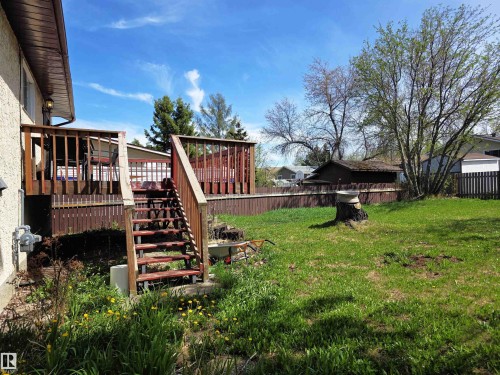 Expansive backyard featuring a multi-level wood deck with railings, direct stairs to the lawn, a wood fence, and mature trees - 4029 55 Avenue, Drayton Valley, AB - Outdoor With Deck Patio Veranda