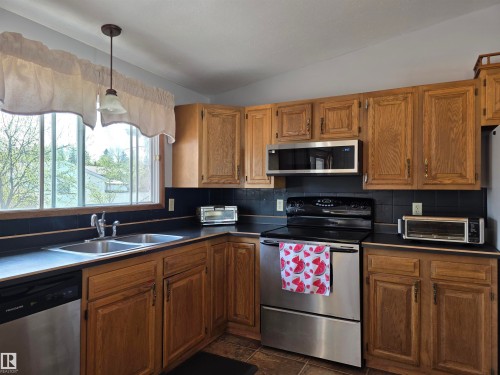 Kitchen featuring wood cabinetry, stainless steel appliances, and a double basin sink - 4029 55 Avenue, Drayton Valley, AB - Indoor Photo Showing Kitchen With Double Sink