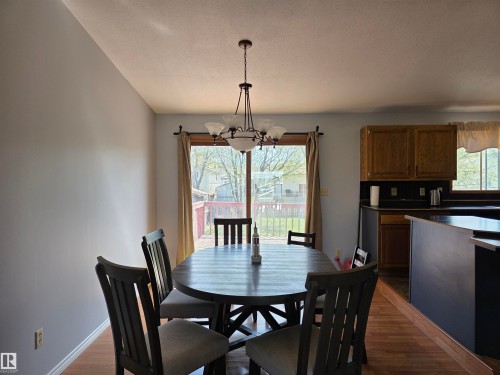 Dining area featuring a contemporary five-light chandelier and wood-finish flooring - 4029 55 Avenue, Drayton Valley, AB - Indoor Photo Showing Dining Room