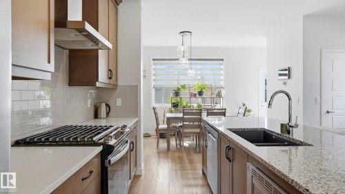 Modern kitchen featuring a stainless steel gas range, coordinating range hood, grey subway tile backsplash, and light wood-finish cabinetry - 17364 2 Street, Edmonton, AB - Indoor Photo Showing Kitchen With Double Sink With Upgraded Kitchen