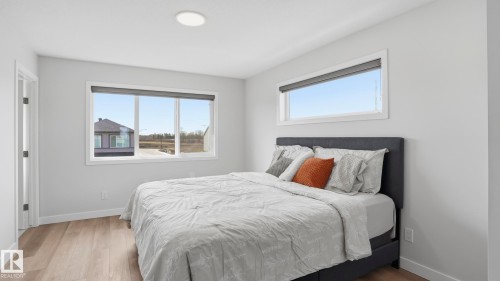 Spacious room featuring light wood-finish flooring, a large window with roller shades, an additional horizontal window, and a recessed ceiling light fixture - 17364 2 Street, Edmonton, AB - Indoor Photo Showing Bedroom