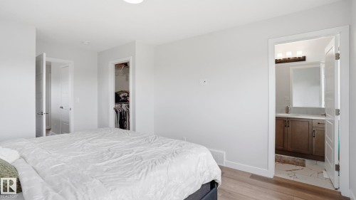 Wood-finish flooring throughout, bright white walls, recessed lighting, and a walk-in closet with built-in shelving and hanging rods - 17364 2 Street, Edmonton, AB - Indoor Photo Showing Bedroom