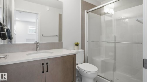 Modern bathroom featuring a single vanity with a solid surface countertop, undermount sink, and dark wood-finish cabinetry - 17364 2 Street, Edmonton, AB - Indoor Photo Showing Bathroom