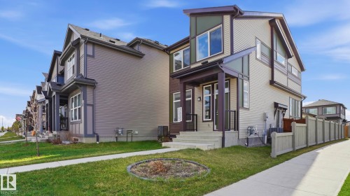Contemporary exterior featuring a covered entry, light-toned siding, dark trim accents, and multiple large windows - 17364 2 Street, Edmonton, AB - Outdoor