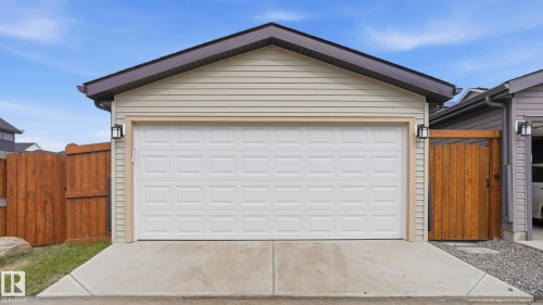 Detached garage featuring a paneled door, light-toned horizontal siding, and dark roofing - 17364 2 Street, Edmonton, AB - Outdoor With Exterior