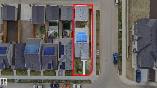 Aerial perspective highlighting the property outlined in red, featuring a gray shingle roof with multiple solar panels - 17364 2 Street, Edmonton, AB - 