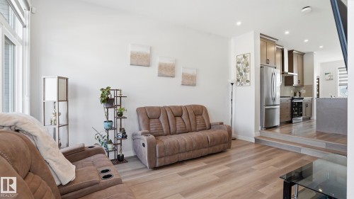 Open-concept living area with wood-finish flooring, white walls, and an abundance of natural light from large windows - 17364 2 Street, Edmonton, AB - Indoor Photo Showing Living Room