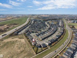 Aerial perspective showcasing a residential development with numerous single-family homes, organized along curved streets - 