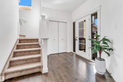 Foyer featuring wood-finish flooring, white trim, and a carpeted staircase with white balusters - 