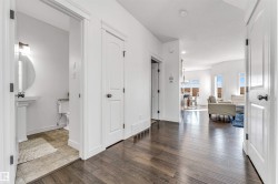 Hallway featuring wood-finish flooring, crisp white walls, and bright white trim - 