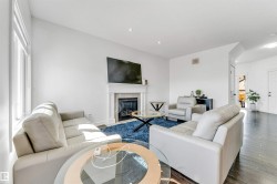 Bright living area featuring dark wood-finish flooring, a white-mantled fireplace, and recessed lighting - 