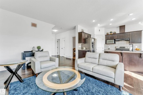 Open-concept living space featuring wood-finish flooring, recessed lighting, and a kitchen with dark cabinetry and stainless steel appliances - 2292 Casey Crescent, Edmonton, AB - Indoor Photo Showing Living Room