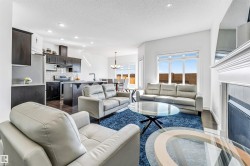 Open-concept living area with dark wood-finish flooring, a white trim fireplace, recessed lighting, and large windows - 