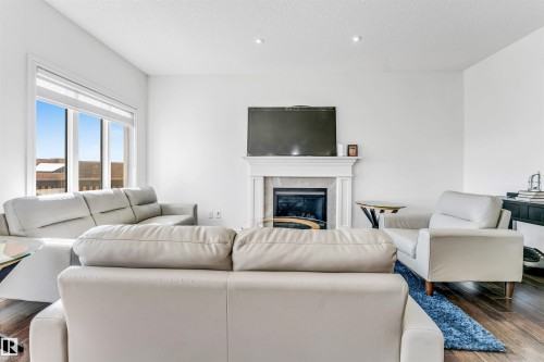 Living area featuring a white mantel fireplace, recessed lighting, expansive windows, and wood-finish flooring - 2292 Casey Crescent, Edmonton, AB - Indoor Photo Showing Living Room With Fireplace