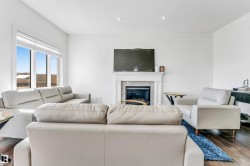 Living area featuring a white mantel fireplace, recessed lighting, expansive windows, and wood-finish flooring - 