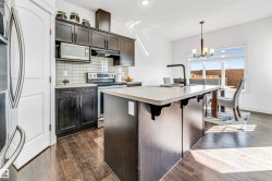 Kitchen featuring dark wood cabinetry, stainless steel appliances, and a light-colored island with an integrated sink - 