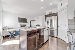 Kitchen island featuring a double-basin sink with a matte black faucet, integrated dishwasher, and dark wood-finish cabinetry - 