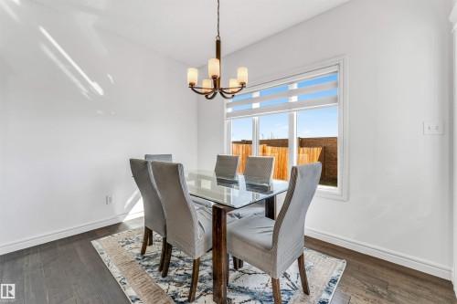 Dining area featuring a prominent window, a decorative chandelier, and dark wood-finish flooring - 2292 Casey Crescent, Edmonton, AB - Indoor Photo Showing Dining Room