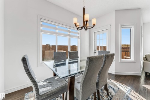 Dining area featuring wood-finish flooring, ample natural light from multiple windows, and a chandelier with glass shades - 2292 Casey Crescent, Edmonton, AB - Indoor Photo Showing Other Room