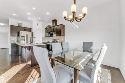 Open-concept dining area featuring a glass-top table, a five-light chandelier, and wood-finish flooring - 