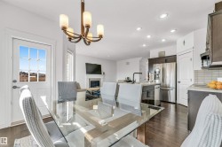 Open-concept living space with dark wood-finish flooring, recessed lighting, and a contemporary chandelier - 