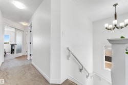 Carpeted hallway with white walls and trim, featuring a flush-mount ceiling light - 