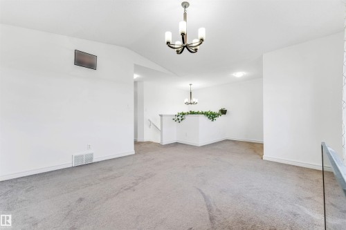 Spacious upper-level landing featuring neutral carpet flooring, white painted walls, and an overhead chandelier light fixture - 2292 Casey Crescent, Edmonton, AB - Indoor Photo Showing Other Room