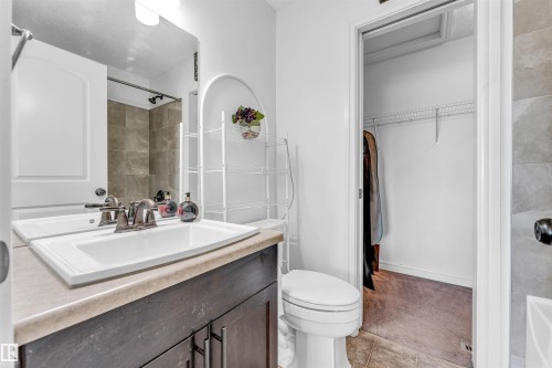 Bathroom vanity featuring a rectangular sink with a chrome faucet, set into a dark wood-finish cabinet with a neutral countertop - 2292 Casey Crescent, Edmonton, AB - Indoor Photo Showing Bathroom